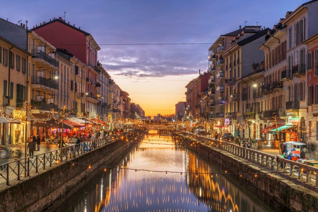 Navigli di Milano al tramonto con ristoranti, luci e riflessi sull’acqua